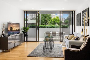 Una sala de estar moderna con televisor, sofá y zona de comedor.