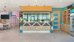 A hotel reception area with a modern design, including a reception desk, seating area, and a large window offering a city view. - Clarion Pointe Spring - Houston North (Spring)