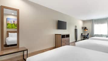 Une chambre d’hôtel avec deux lits, un bureau, une chaise, un téléviseur à écran plat, un miroir et un tableau au mur.