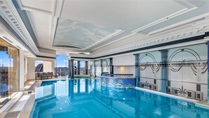 Une grande piscine intérieure offrant une vue dégagée sur le paysage urbain à travers les fenêtres.