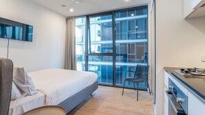 Una habitación de hotel moderna con una cama grande, un escritorio con estufa, una silla y un televisor montado en la pared.