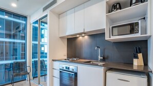 Una cocina moderna con horno empotrado, un lavamanos y un microondas. Hay una ventana que proporciona luz natural y vistas al exterior.