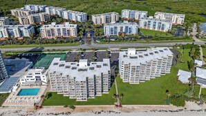 Un complejo residencial de edificios altos con varios balcones, una piscina y una zona de playa.