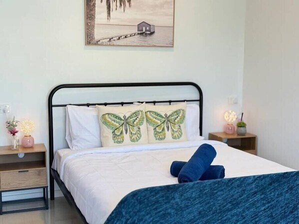 A neatly made bed with a butterfly pillow, a bedside table with a lamp, and a wall-mounted picture. - Convenient 2BR Unit in Salisbury | near TrainandBus (Salisbury)