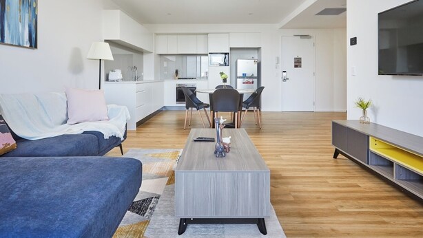 A modern living room with a sofa, coffee table, and a TV on a stand.