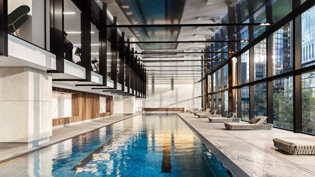 Une piscine intérieure offrant une vue dégagée sur la ville grâce à de grandes fenêtres.