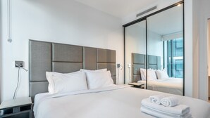 A modern hotel room with a large bed, a built-in wardrobe, and a large mirror reflecting the room. - Elegantandmodern 1 bedroom Apartment Infinity Pool (Fortitude Valley)