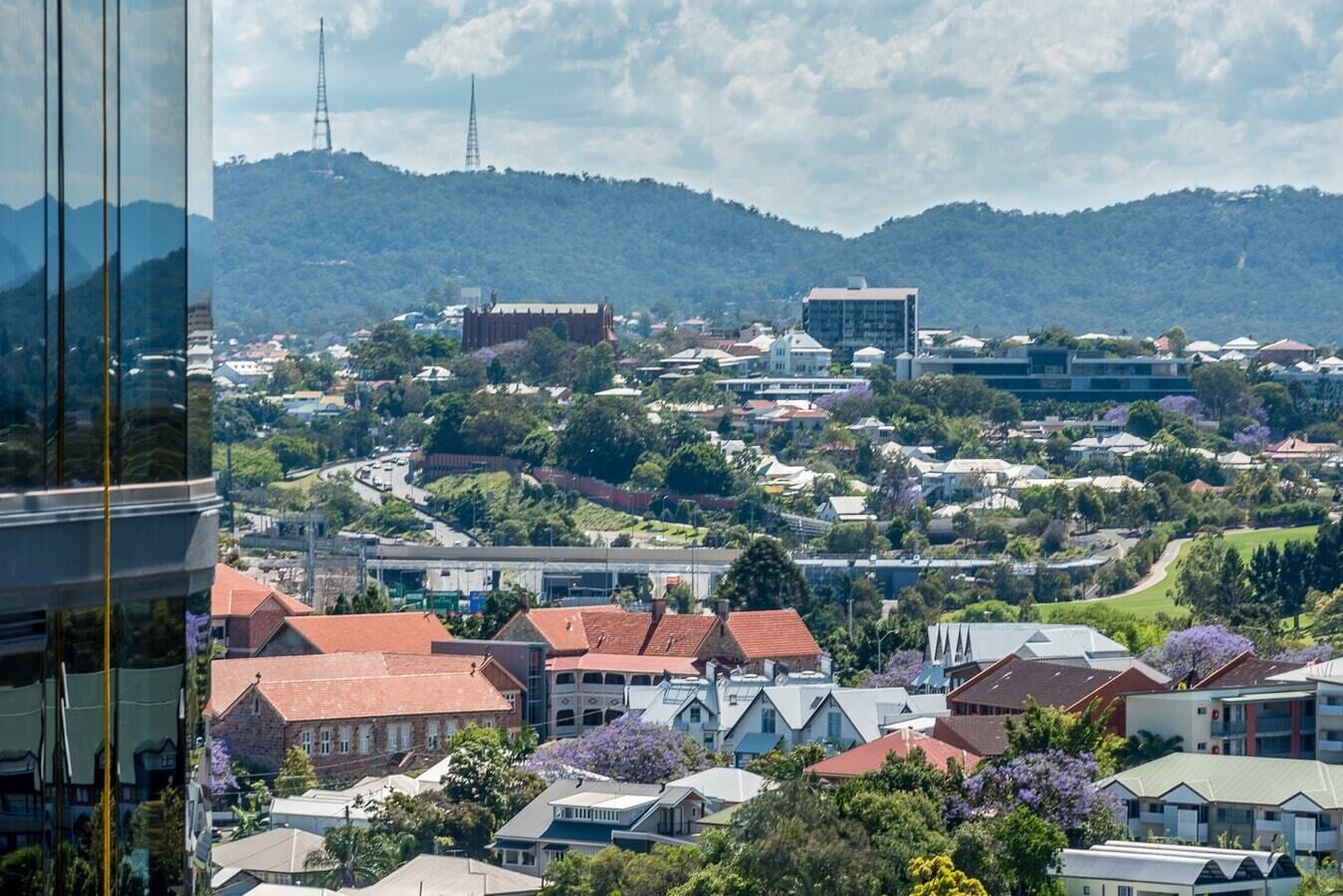 A residential area with houses, a large building, and hills in the background.