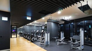 A modern gym with cardio machines, free weights, and a wooden floor.