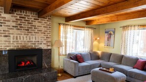 Ein gemütliches Wohnzimmer mit Kamin, einem Ecksofa und Holzboden.