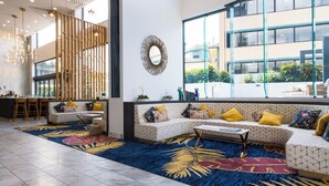 A modern interior with a seating area, a dining space, and large windows offering a view of the outside. - Convenient Located 2-Bedroom Apartment In Surfers (Surfers Paradise)