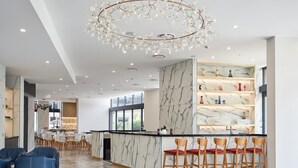 A modern hotel lobby with a marble reception desk, bar area, seating, and a large chandelier. - Convenient Located 2-Bedroom Apartment In Surfers (Surfers Paradise)