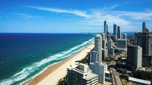 Un paysage urbain côtier avec de hauts immeubles, une plage et un ciel bleu dégagé.