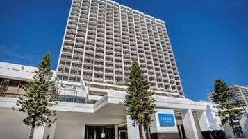 A tall hotel with a modern design, featuring a prominent entrance and a sign for 'Mantra on View Hotel.'