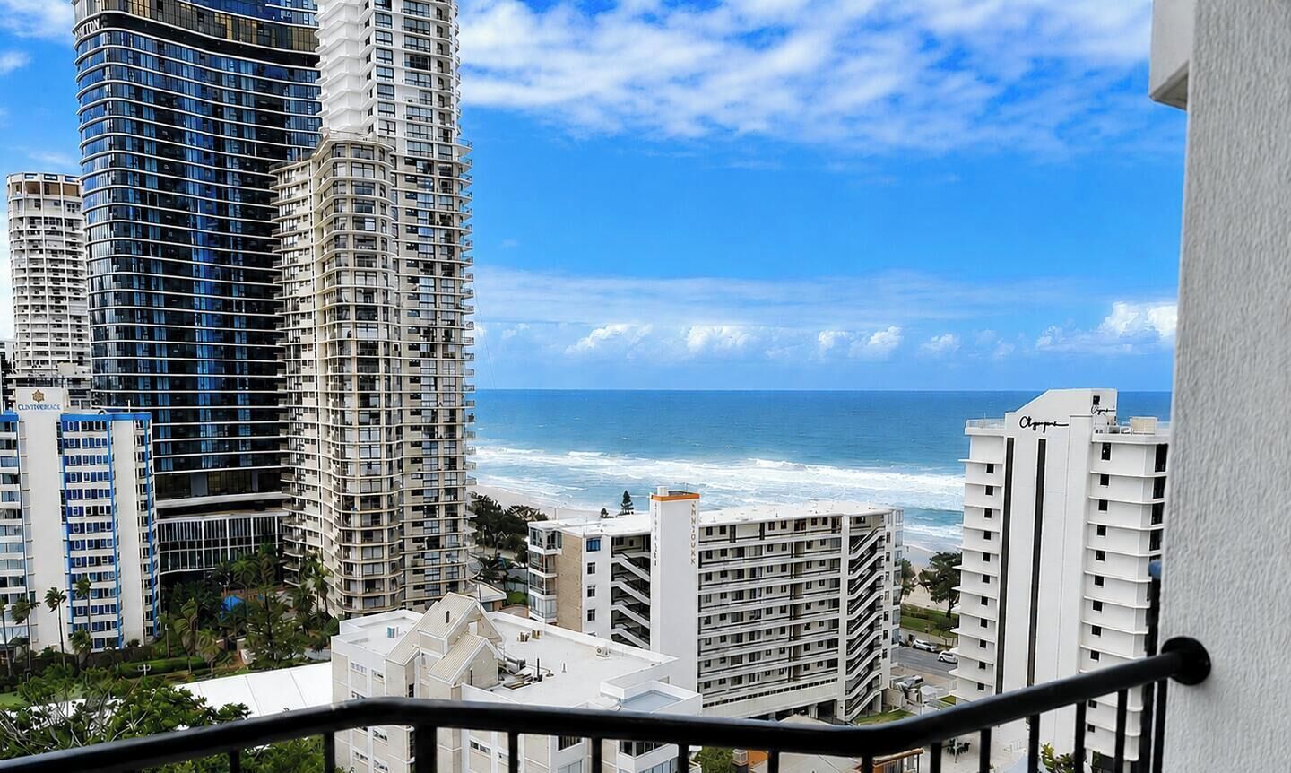 A coastal cityscape with high-rise buildings, a clear sky, and the ocean in the background.