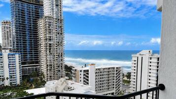 A coastal cityscape with high-rise buildings, a clear sky, and the ocean in the background.