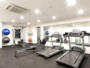 Ein Fitnessstudio mit Laufbändern, Gymbällen und Krafttrainingsgeräten.