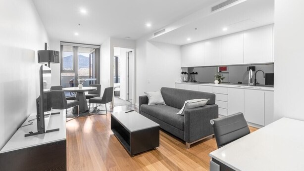 Un espacio habitable moderno y compacto con comedor, sofá y kitchenette.