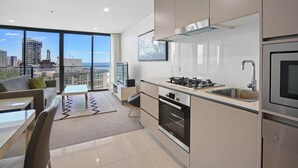 A modern kitchen with a built-in oven, a stainless steel sink, and a large window overlooking a cityscape. - 1BR for 4  | Unbeatable Ocean View | Walk to Beach (Surfers Paradise)