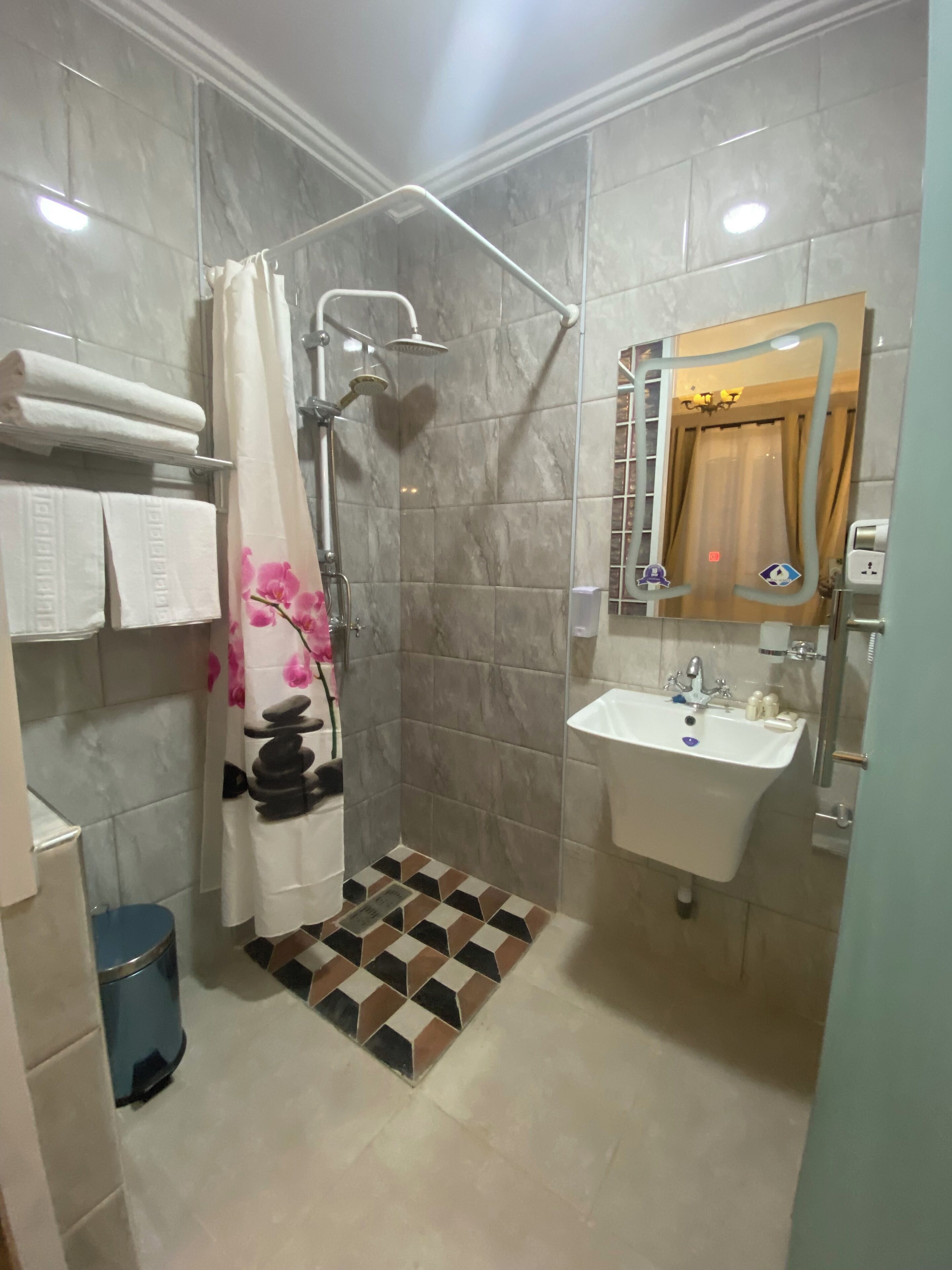 A bathroom with a shower, a sink, and a mirror.