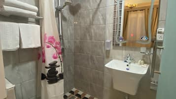 A bathroom with a shower, a sink, and a mirror.