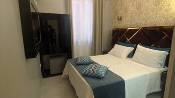 Une chambre d’hôtel avec un lit, une télévision, un lustre et un mur orné de motifs.