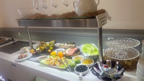 Un bufé con diversos alimentos y una selección de copas de vino blanco.