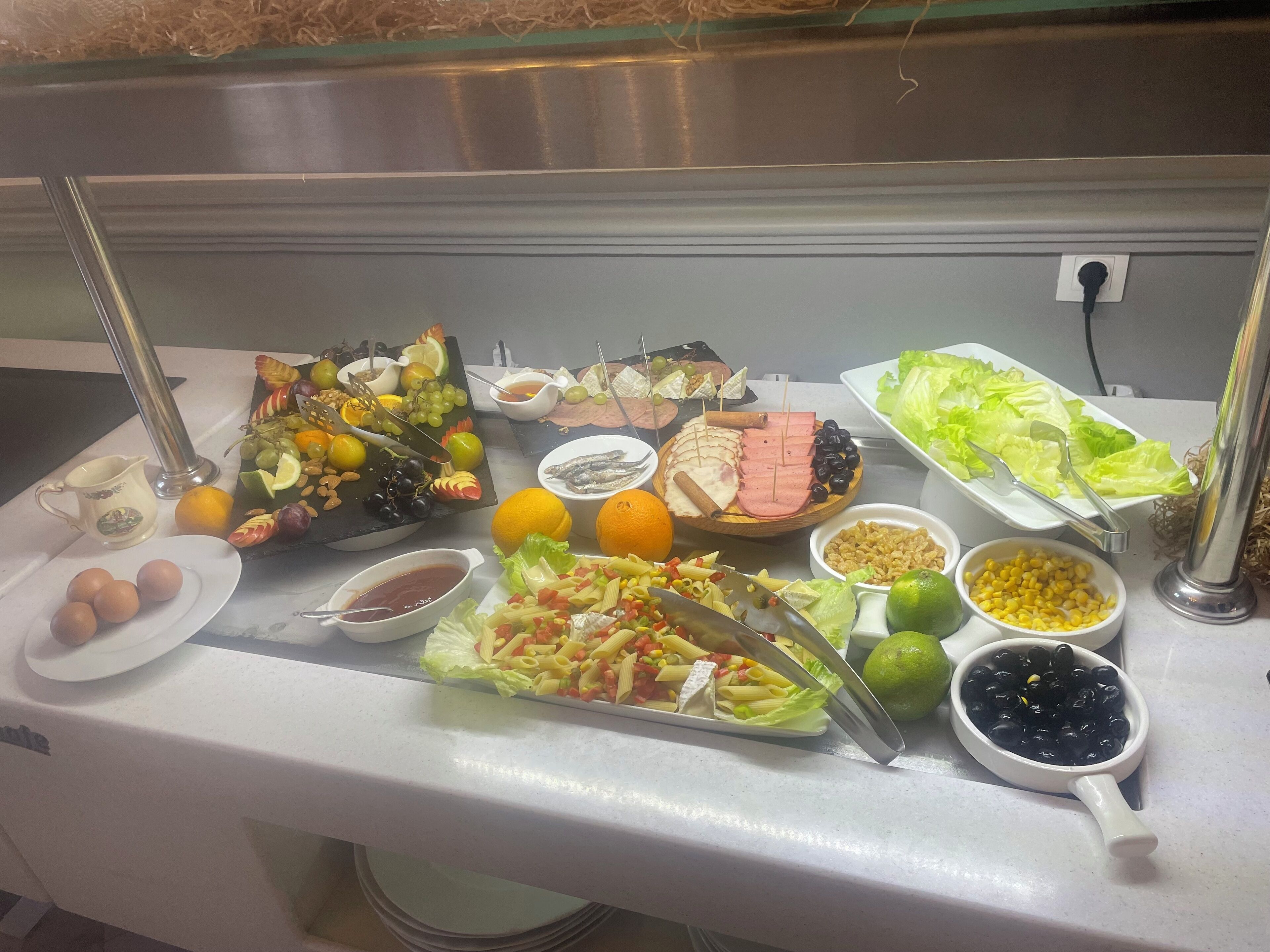 Een buffet met diverse gerechten, waaronder fruit, groenten, pasta en vlees.