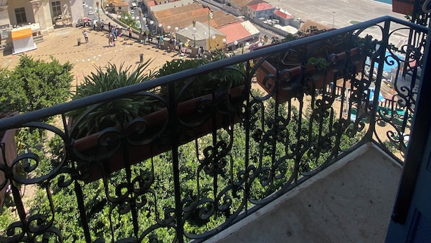 A balcony with wrought iron railings and potted plants. - Hotel de letoile (Béjaïa)
