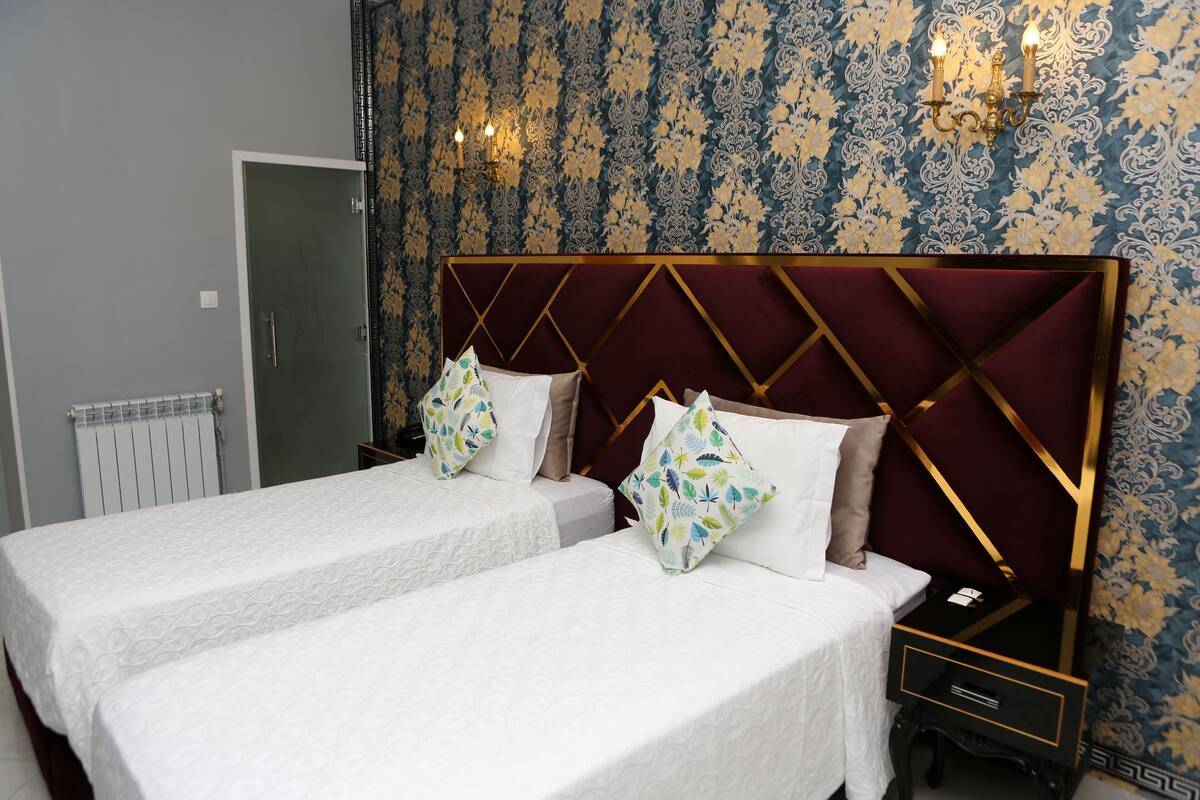 A double bed with a headboard, two bedside tables, and a nightstand with a lamp.