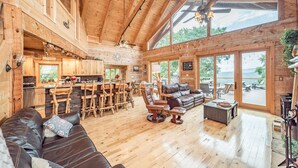 L’intérieur de cette vaste cabane en rondins est doté d’un grand espace à manger, de sièges en cuir et de grandes fenêtres offrant une vue sur l’extérieur.