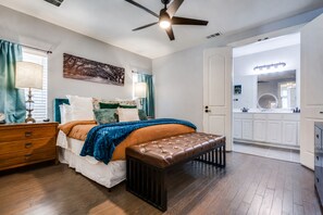 Une chambre à coucher avec un lit, une table de chevet, une lampe et un ventilateur de plafond.
