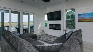A living room with a gray sectional sofa, a flat-screen TV mounted on the wall, and a fireplace.