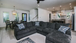 A modern living room with a sectional sofa, dining area, and kitchen.