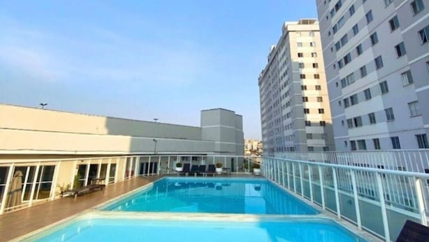 A rooftop pool with lounge chairs, surrounded by high-rise buildings. - Apartamento Park Quinet  (Juiz de Fora)