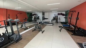 A gym with treadmills, elliptical machines, and weightlifting equipment. - Apartamento Park Quinet  (Juiz de Fora)