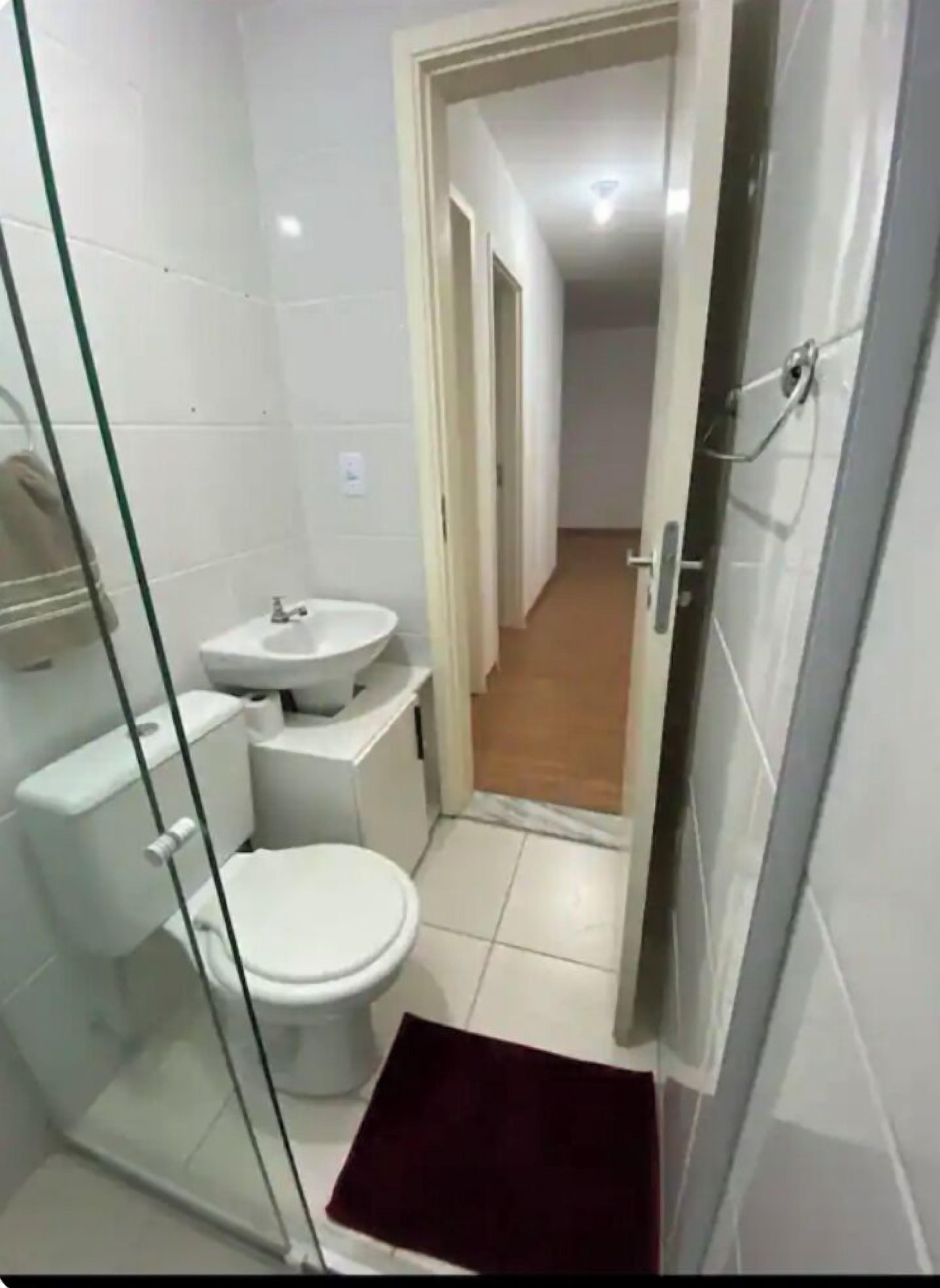 A small, clean bathroom with a toilet, sink, and glass shower enclosure.