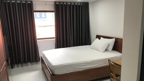 A hotel room with a wooden bed, white bedding, and a view through a window with curtains. - MoonStay (Ho Chi Minh City)