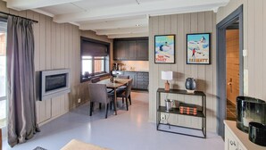Ein modernes Wohnzimmer mit Essbereich, Küche und einem an der Wand befestigten Fernseher.
