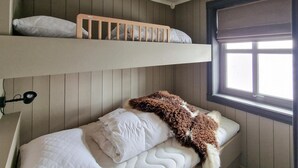 Ein Stockbett mit Fenster darüber, eine Nachttischlampe und eine flauschige Decke auf dem unteren Bett.