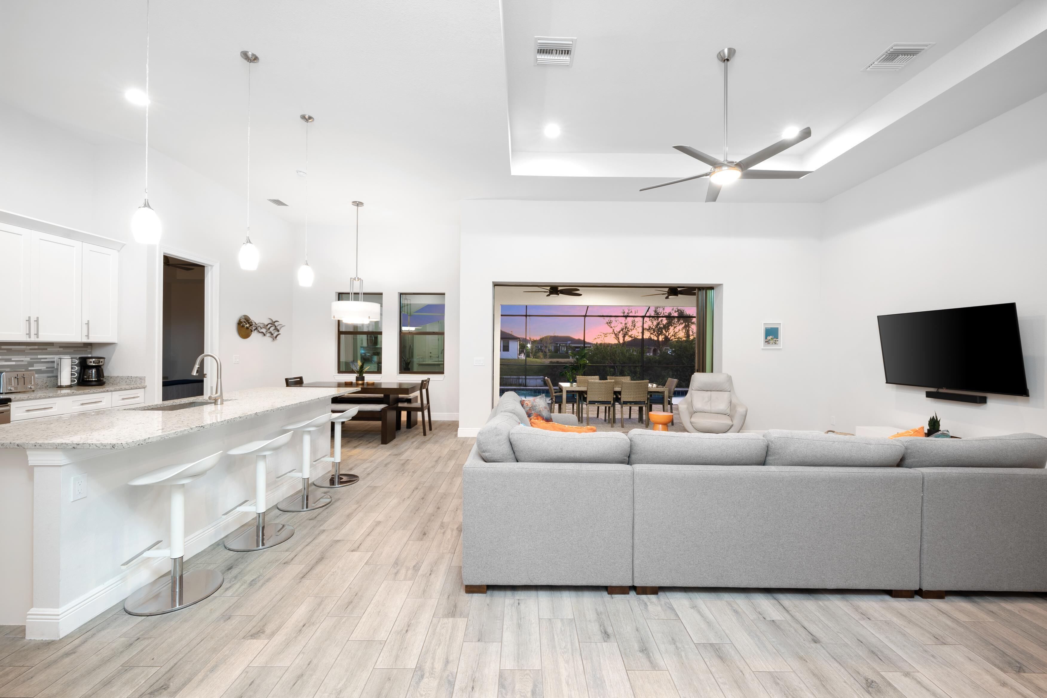 A modern kitchen with white cabinetry, a bar area, and a dining space.