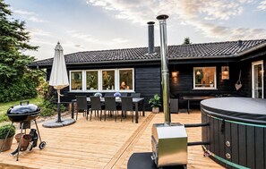 Eine Holzterrasse mit Grill, Whirlpool und Sitzgelegenheit im Freien.