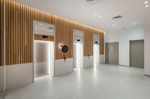 A modern elevator area with wooden paneling and a clean, tiled floor. - Beautiful Ocean View Apartment Signature Broadbeach (Broadbeach)