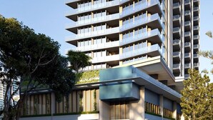 Un edificio moderno de varios pisos con balcones, un patio central y vegetación.