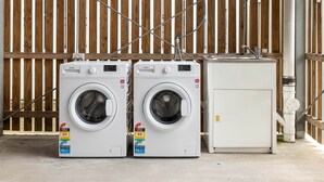 Two front-loading washing machines and a dryer unit in a utility area with a wooden fence in the background. - Private Rocklea 2BR | Near Shops | Kitchen | 318D2 (Rocklea)