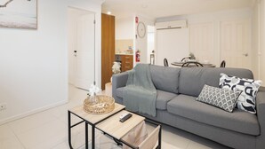 A modern living room with a grey sofa, a small wooden coffee table, and a remote control. - Private Rocklea 1BR | Good Location | 216D1 (Rocklea)