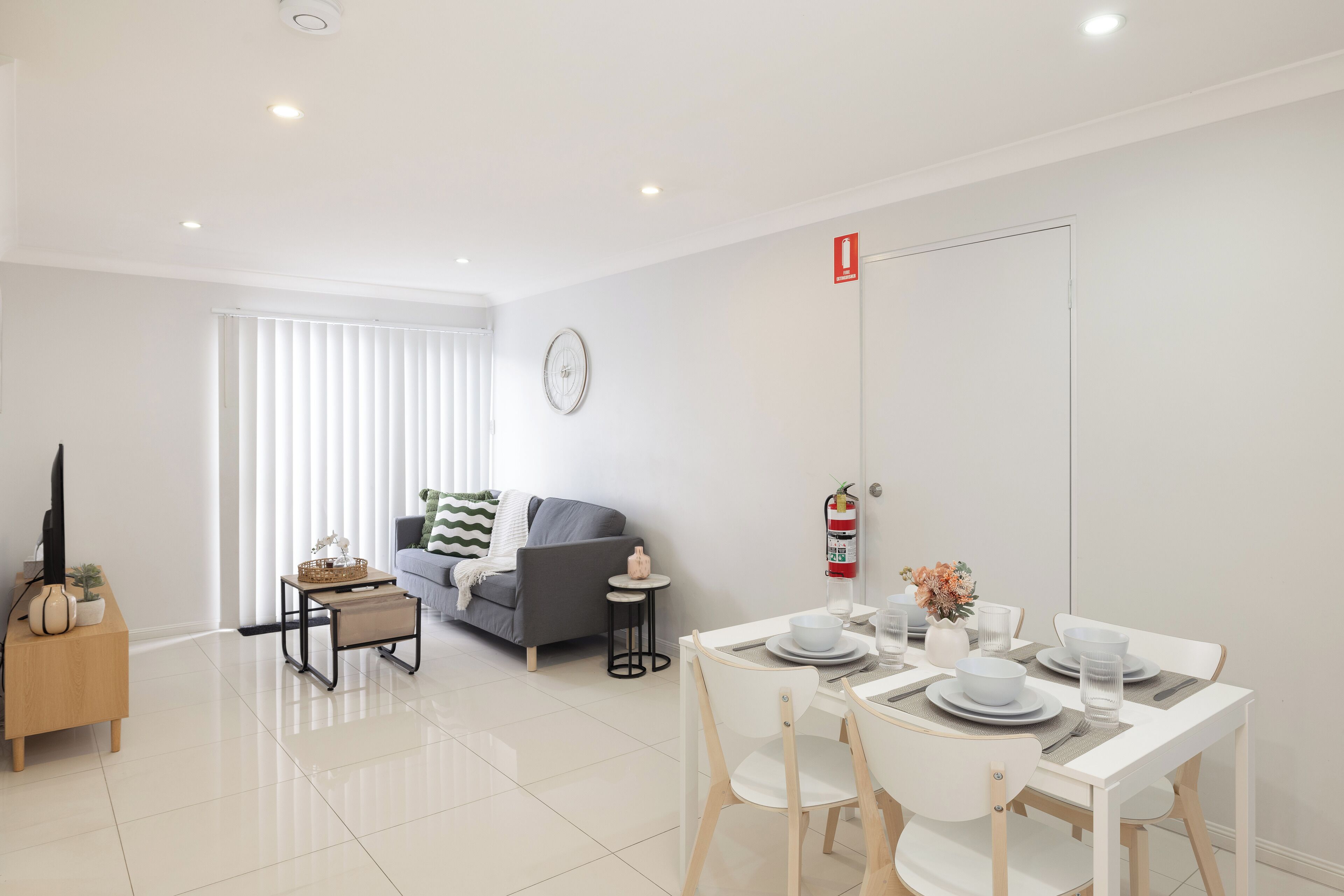 A modern living room with a sofa, a coffee table, and a dining area with a table set for two.