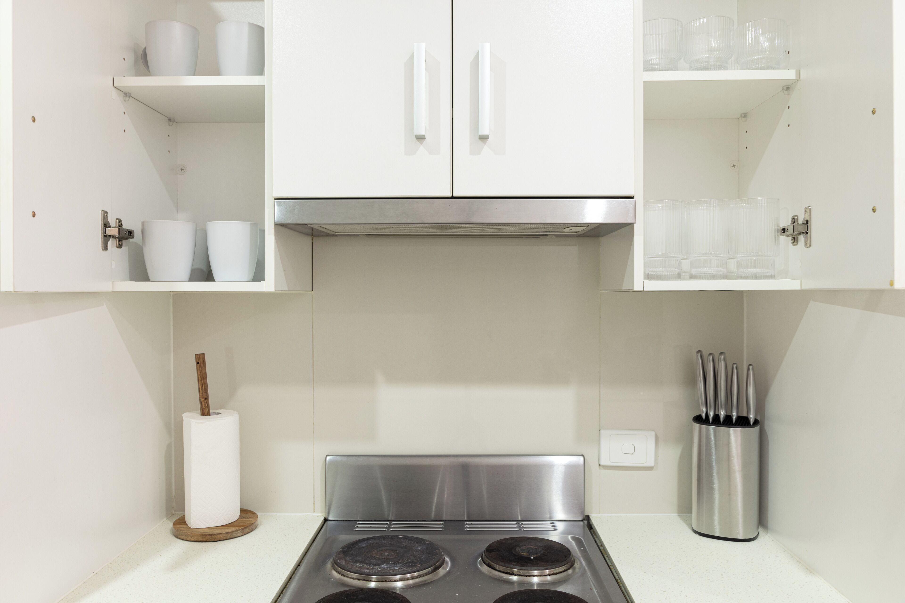 A kitchen with white cabinets, a stainless steel stove, and a knife block.