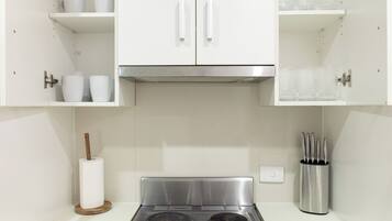 A kitchen with white cabinets, a stainless steel stove, and a knife block.