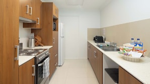 Una cocina moderna con armarios de madera, electrodomésticos de acero inoxidable y encimera blanca.